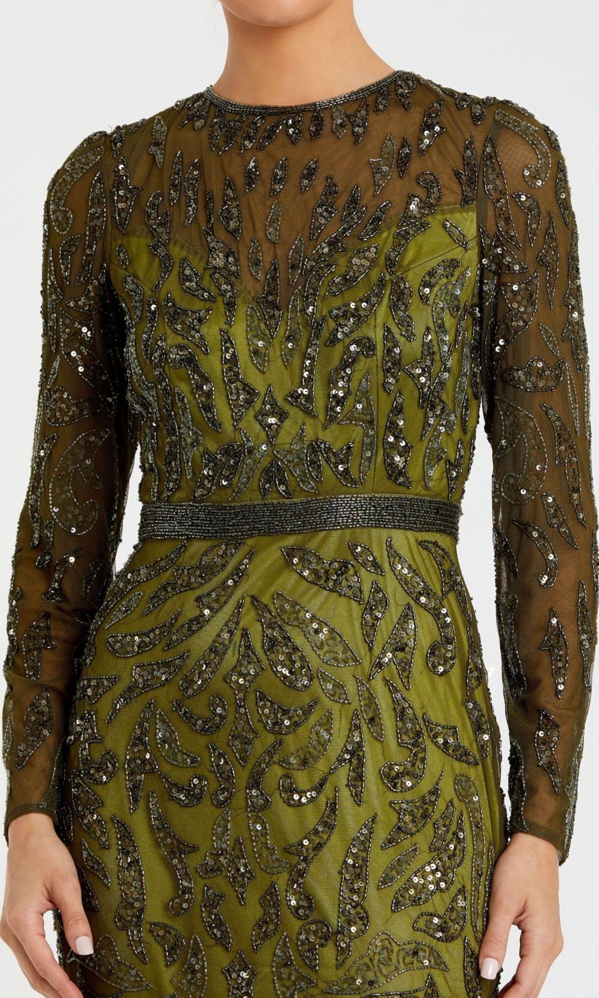 A person wearing the Mac Duggal 5124, a long sleeve sequin formal dress in olive green with black beaded leaf patterns and a beaded waistband, styled as a modest evening gown.